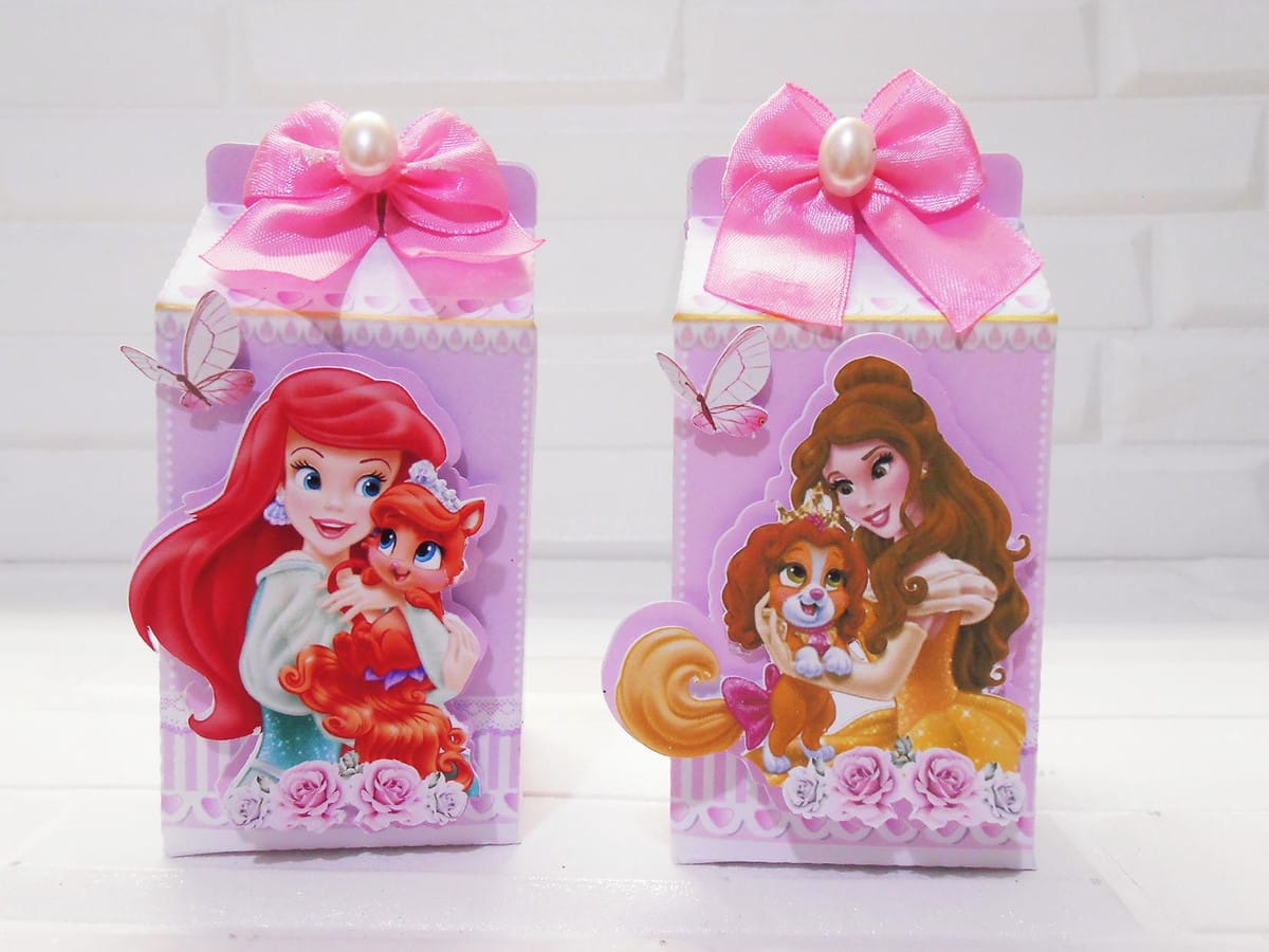 Monte uma Festa Princesas Disney com Kit Digital Completo 4 Duas caixas decoradas com princesas, laços rosa e pérolas em fundo branco.