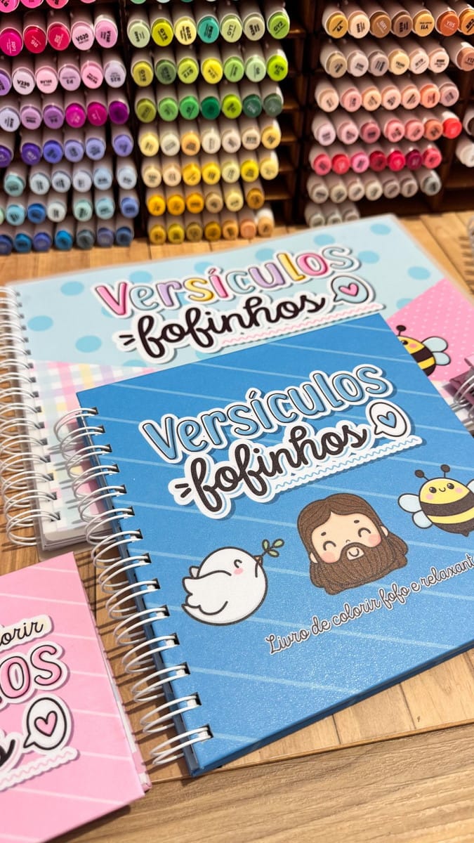 Pack Livro de Colorir Versículos Bíblicos para Sublimação 2 Cadernos com capas coloridas e ilustrações fofas sobre fundo de madeira.