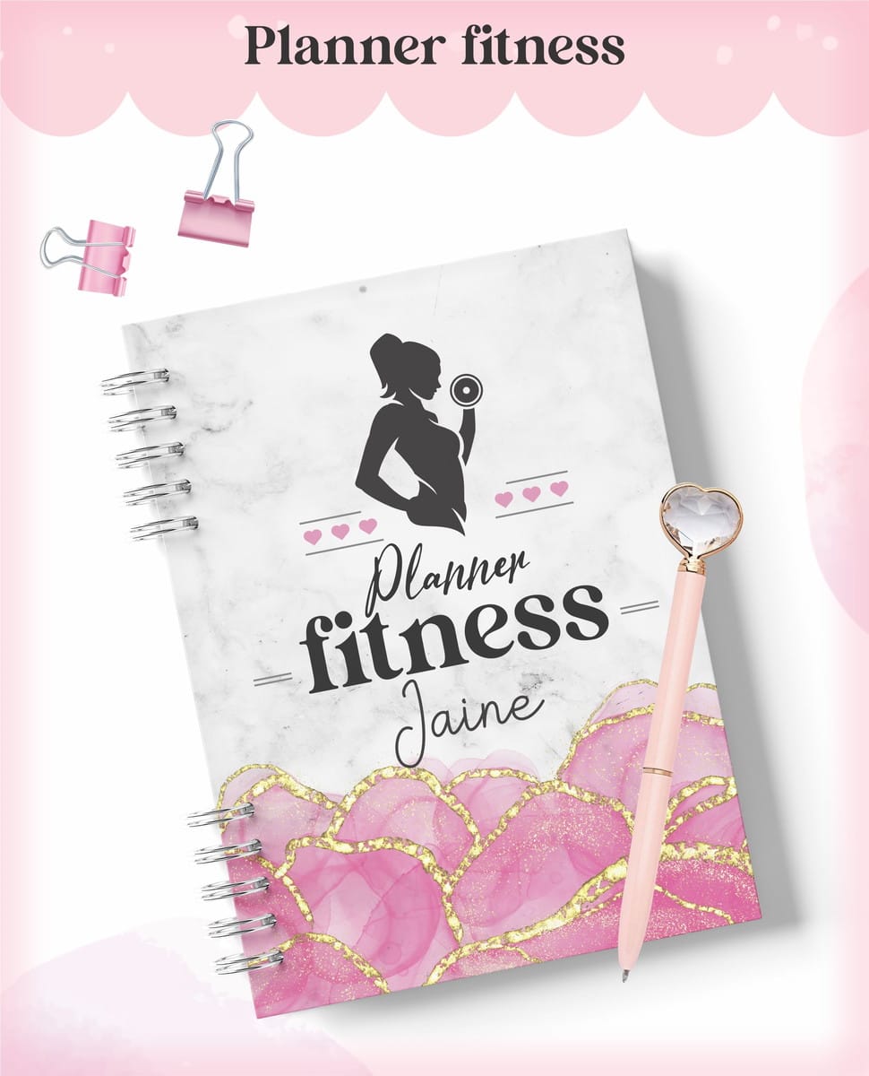 Planner Fitness Feminino Digital 2023 para Imprimir 1 Caderno espiral com capa temática fitness, caneta com pedra coração e clips rosa.