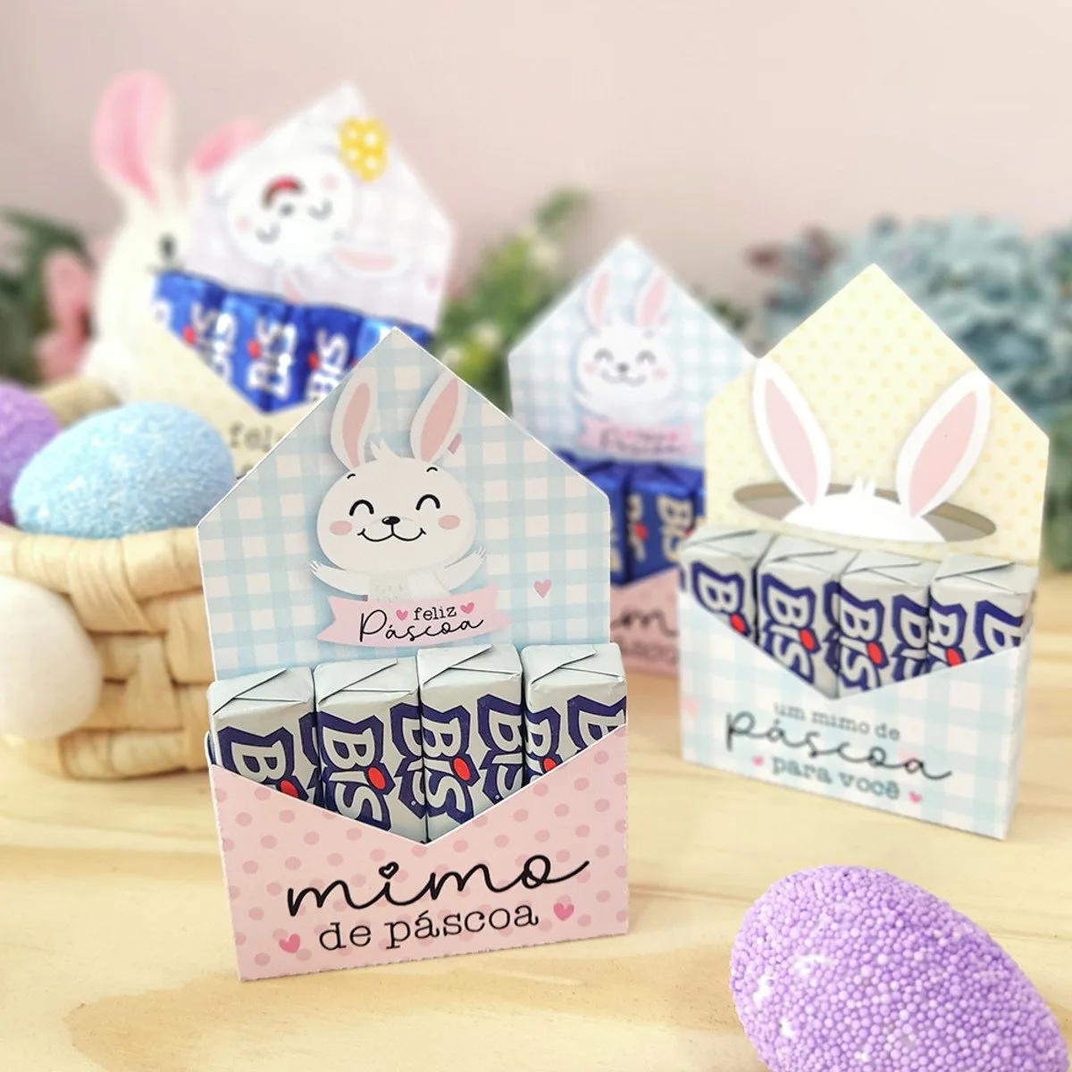 Porta Bis Páscoa 2 Caixinhas decoradas de Páscoa com chocolates e coelhos impressos sobre fundo de madeira.