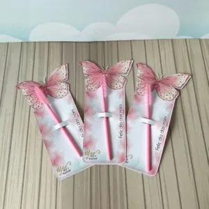 Três suportes de papel decorados com borboletas contêm escovas de cílios cor-de-rosa.